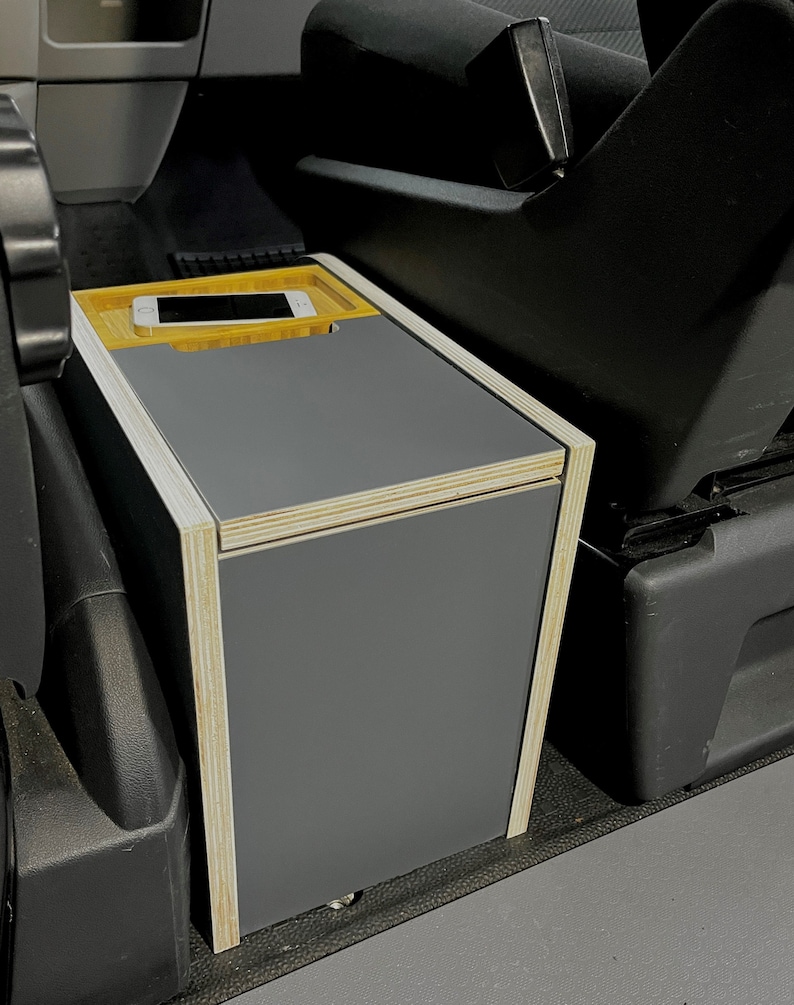 Puede incluir: Una caja de almacenamiento gris con un marco de madera y una peque&ntilde;a bandeja de madera en la parte superior. La bandeja tiene un tel&eacute;fono m&oacute;vil.