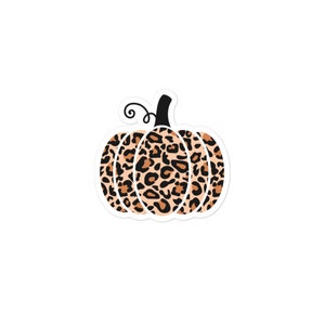 May include: A sticker featuring a pumpkin design with a leopard print pattern in shades of brown and tan. The pumpkin has a black stem and a curly vine. The sticker is white around the edges.