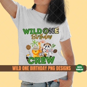 K&ouml;nnte beinhalten: Ein wei&szlig;es T-Shirt mit einem gr&uuml;nen und gelben Grafikdesign, auf dem "Wild One Birthday Crew" steht. Die Grafik zeigt eine Gruppe von Dschungeltieren, darunter ein L&ouml;we, ein Zebra, ein Panda und ein Affe.