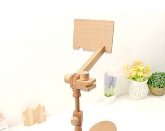 May include: A wooden phone stand with adjustable height and angle. The stand has a rectangular base and a long, adjustable arm that can be positioned to hold a phone or tablet.