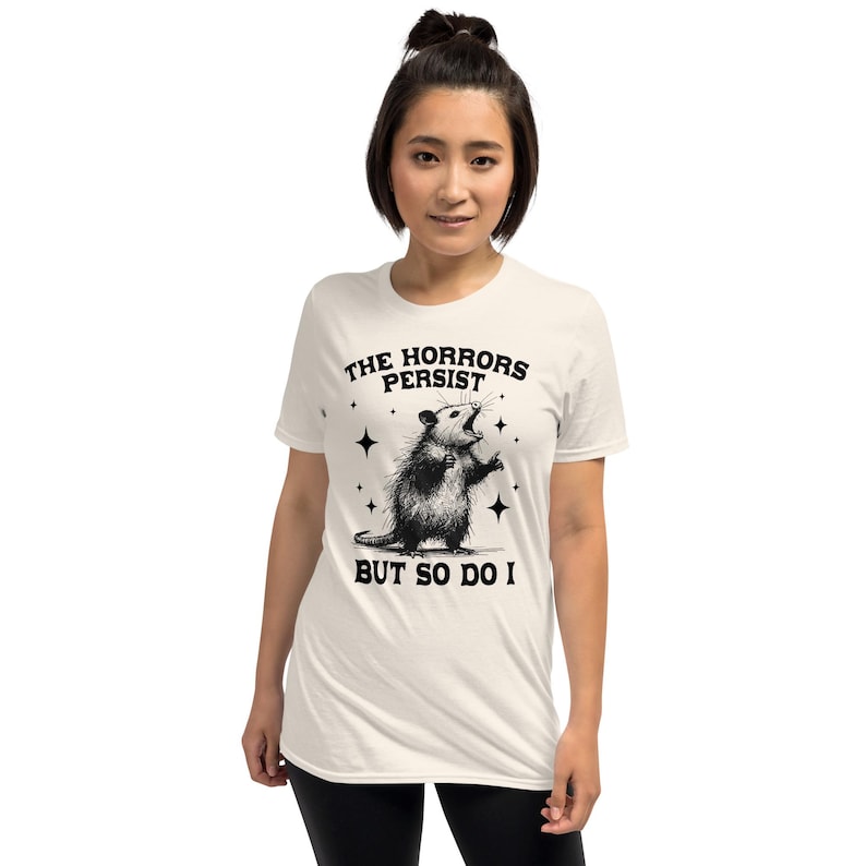 Unisex T-Shirt mit einem schreienden Opossum im Retro Stil und der Aufschrift: The Horrors Persist But so do I.