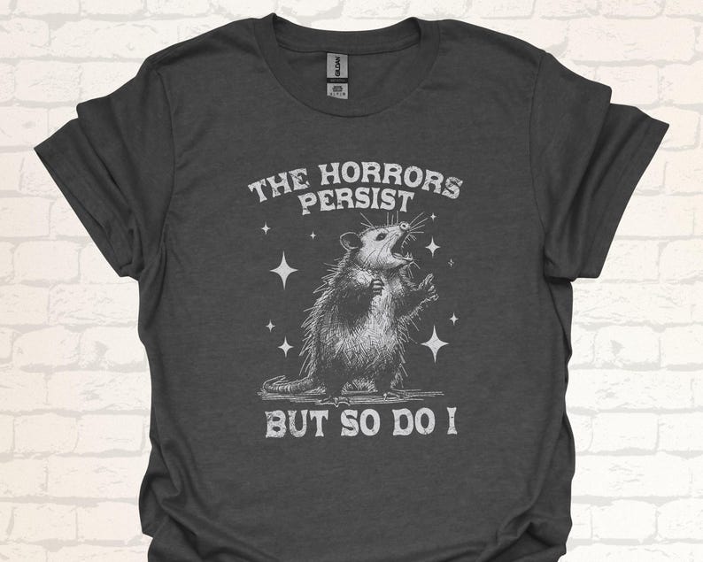 Unisex T-Shirt mit einem schreienden Opossum im Retro Stil und der Aufschrift: The Horrors Persist But so do I.