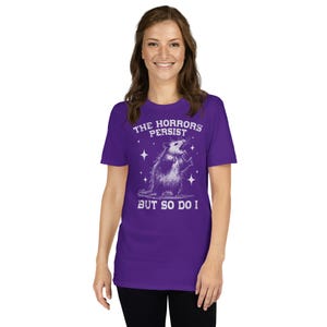 Unisex T-Shirt mit einem schreienden Opossum im Retro Stil und der Aufschrift: The Horrors Persist But so do I.