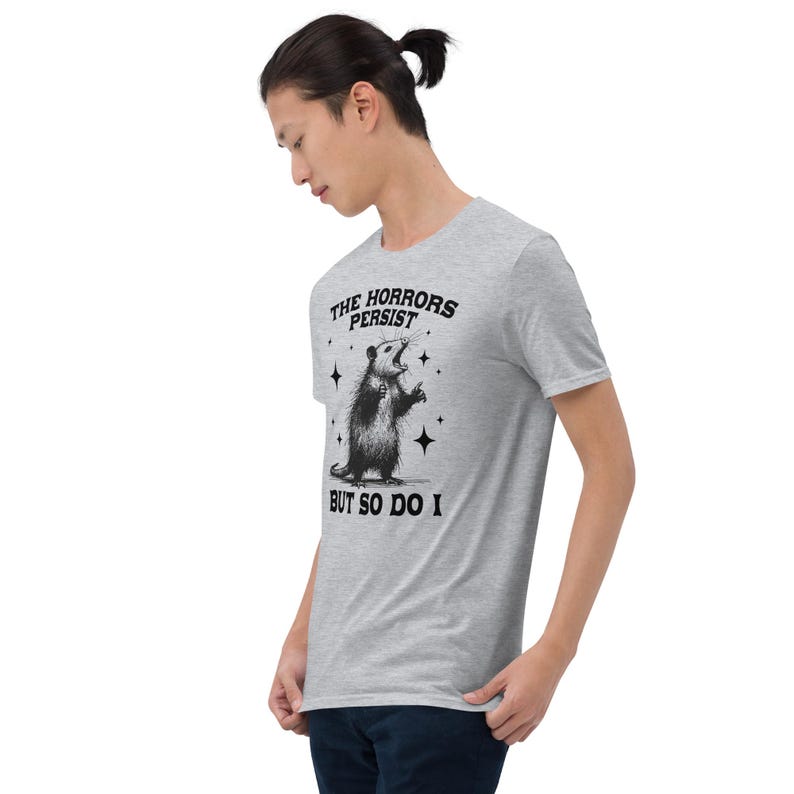 Unisex T-Shirt mit einem schreienden Opossum im Retro Stil und der Aufschrift: The Horrors Persist But so do I.