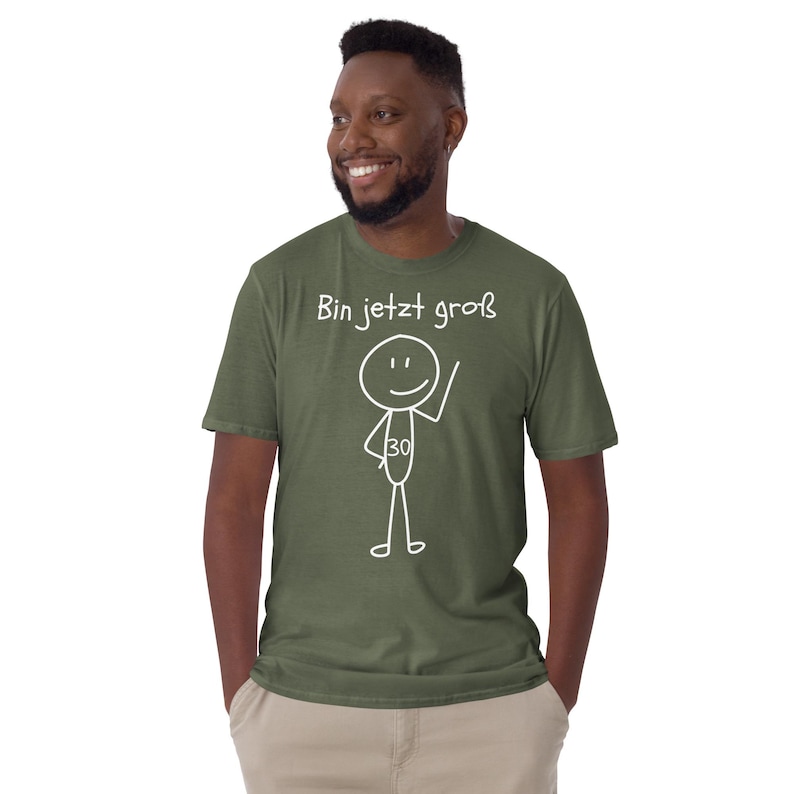 May include: Olive green t-shirt with the text "Bin jetzt gro&szlig;" and a stick figure with the number 30. The stick figure is waving. The t-shirt is made of a soft material.