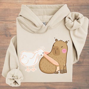 面白いカピバラのパーカー |かわいいカピバラとペリカンのミームデザインのセーター |かわいい動物グラフィックセーター |友達への面白い贈り物