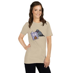 Unisex T-Shirt mit einer Taube die ein Buch liest auf dessen Einband How to poop on people steht.
