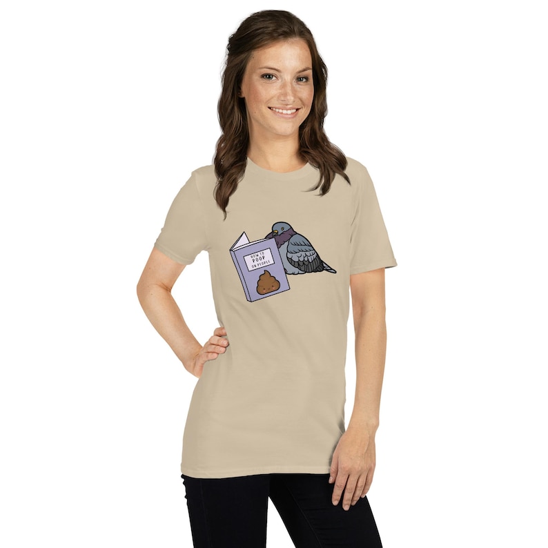 Unisex T-Shirt mit einer Taube die ein Buch liest auf dessen Einband How to poop on people steht.