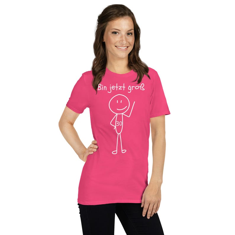 May include: A bright pink t-shirt with the German phrase "Bin jetzt gro&szlig;" and a stick figure design. The stick figure has a smiley face and the number 30. The shirt is a short-sleeved crew neck.