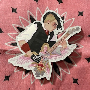 Op de afbeelding: Een sticker met een gestileerde illustratie van een persoon die gitaar speelt, met engelen vleugels. De persoon draagt een zwart vest, een wit overhemd en een rode polsband. De gitaar heeft hartvormige inlegwerk. De sticker heeft een roze en witte achtergrond.