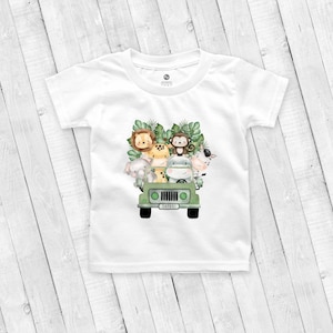 May include: White t-shirt with a green jeep carrying a lion, monkey, giraffe, elephant, hippopotamus, and zebra. The jeep has a license plate that says "SAFARI".