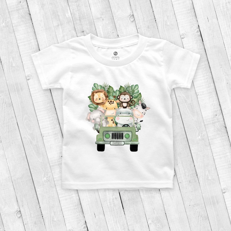 May include: White t-shirt with a green jeep carrying a lion, monkey, giraffe, elephant, hippopotamus, and zebra. The jeep has a license plate that says "SAFARI".