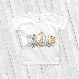 May include: White t-shirt with a watercolor illustration of a group of safari animals, including a zebra, giraffe, elephant, lion, and hippopotamus. The animals are surrounded by green leaves.