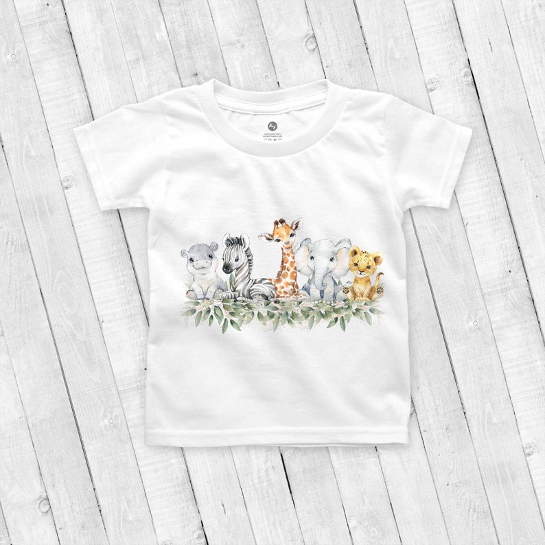 May include: White t-shirt with a watercolor illustration of a group of safari animals, including a zebra, giraffe, elephant, lion, and hippopotamus. The animals are surrounded by green leaves.