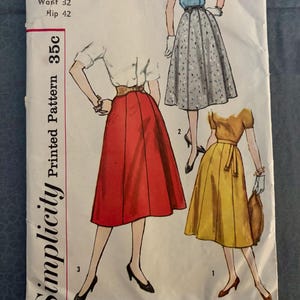 May include: A Simplicity printed pattern envelope 2469 for a skirt with a waist of 32 inches and hip of 42 inches. The illustration shows three variations of a skirt in red, grey with a blue pattern, and yellow, paired with various tops.