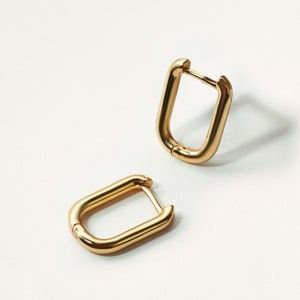 May include: A pair of gold hoop earrings with a rectangular shape.