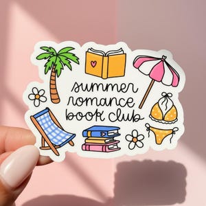 May include: A white sticker with a summer theme. It features a palm tree, a beach chair, an open book with a heart, a pink and white umbrella, a bikini, flowers, and the text "summer romance book club."