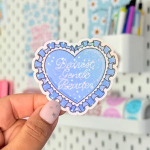 May include: A heart-shaped sticker with the text "Dearest Gentle Reader" in a cursive font. The sticker has a light blue background with glitter and a ruffled border. Small stars are scattered around the text.