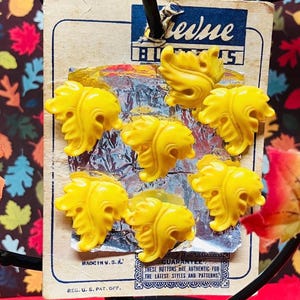 May include: A card with a blue and white label that reads "Genuine Buttons" and features seven yellow plastic buttons shaped like stylized leaves. The card also reads "Made in U.S.A." and "Reg. U.S. Pat. Off."