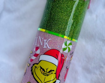 May include: A green and pink glitter tumbler with a Grinch design and the words "Think" and "Grinch". The top of the tumbler is decorated with pink frosting and sprinkles.