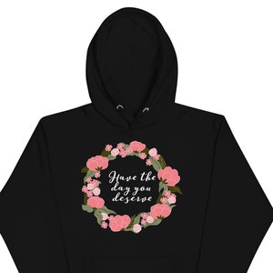 May include: Black hooded sweatshirt with a floral wreath design and the text "Have the day you deserve" in white.