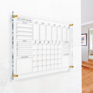 May include: A clear acrylic dry-erase board with a weekly calendar, to-do list, menu, and grocery list sections. The board has the text "The White Family" at the top.
