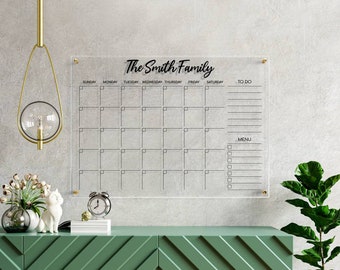 May include: A clear acrylic dry erase calendar with a black frame and the text "The Smith Family" at the top. The calendar has spaces for each day of the week, a to-do list, and a menu section.