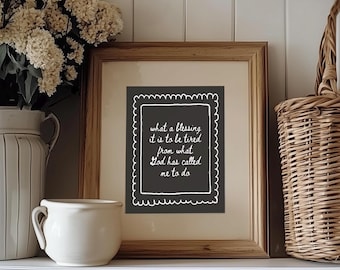 Puede incluir: Una impresión enmarcada con el texto "what a blessing it is to be tired from what God has called me to do". La impresión está en un marco de madera y se exhibe en un estante blanco con un jarrón blanco de flores y una cesta de mimbre.