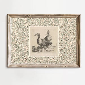 May include: Framed vintage print featuring two ducks. The artwork is a detailed black and white illustration set against a cream-colored background. The frame is a light brown wood with a floral patterned border.