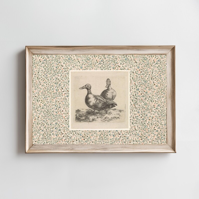 May include: Framed artwork featuring a detailed black and white etching of two ducks. The ducks are depicted in a naturalistic style. The frame is light wood with a floral patterned border in shades of green, pink, and cream.