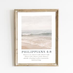 May include: Framed print featuring a serene beach scene with soft blue and beige tones. The artwork includes the text "PHILIPPIANS 4:8" and a related quote in a dark blue font, set against a white background.