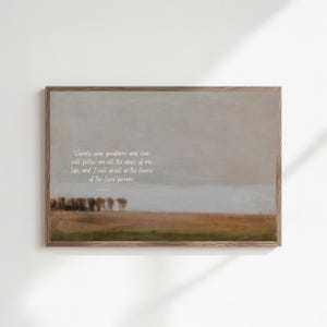 May include: A framed landscape art print with a muted color palette. The artwork features a field, trees, and a cloudy sky. The text "Surely your goodness and love will follow me all the days of my life, and I will dwell in the house of the Lord forever." is written in white.