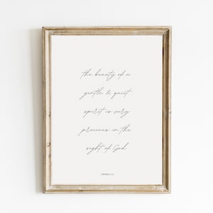 Puede incluir: Una impresión enmarcada con un fondo beige claro y una elegante escritura negra. El texto dice: "la belleza de un espíritu gentil y tranquilo es muy preciosa a los ojos de Dios". El marco es de color marrón claro.