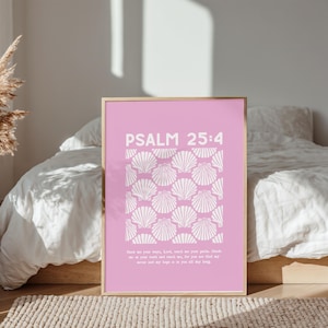 May include: A framed pink print with the text "PSALM 25:4" in white. Below the text is a pattern of white seashells. The bottom of the print contains additional white text. The frame is gold.