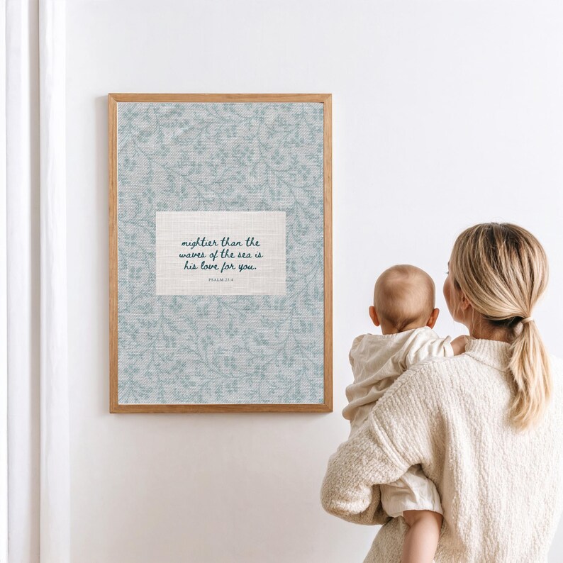 Puede incluir: Un marco con un estampado floral azul claro y el texto "mightier than the waves of the sea is his love for you." El marco es de madera. Una persona sostiene a un beb&eacute;.