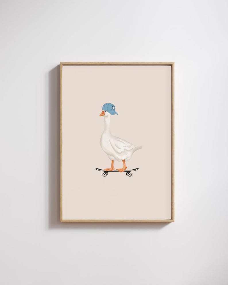 May include: A framed print featuring a white goose wearing a blue baseball cap and riding a skateboard. The goose has orange feet and a yellow beak. The background is a solid light beige color.