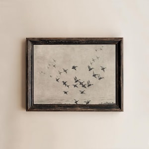 May include: A framed print featuring a flock of birds in flight against a muted, neutral background. The birds are depicted in silhouette, creating a sense of movement. The frame is dark with a distressed finish.