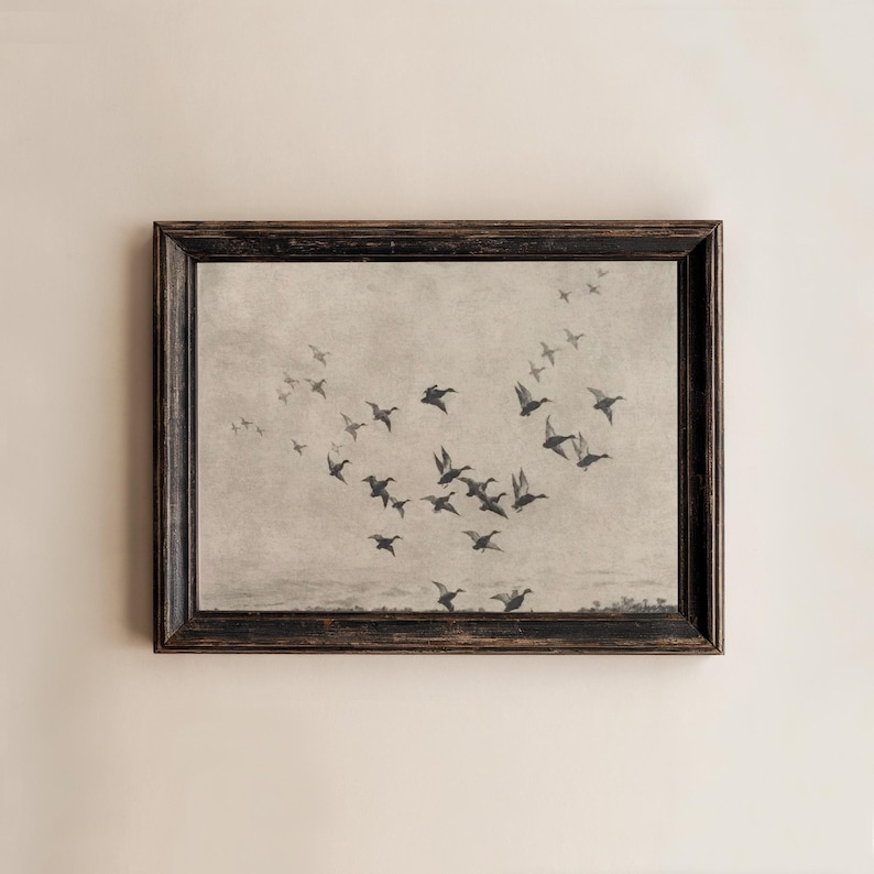 May include: A framed print featuring a flock of birds in flight against a muted, neutral background. The birds are depicted in silhouette, creating a sense of movement. The frame is dark with a distressed finish.