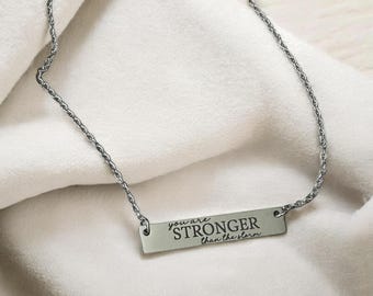 May include: Silver necklace with a bar pendant that reads "you are STRONGER than the storm".