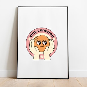 Peut inclure: Une affiche encadrée avec un cadre noir. L'illustration de style rétro représente un personnage orange souriant tenu par deux mains, entouré d'un cercle rose avec le texte "stay centered".