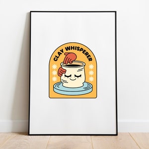 Könnte beinhalten: Ein gerahmter Druck mit einer gelben, orangefarbenen und blauen Illustration einer Hand, die einen Tontopf auf einer Töpferscheibe formt. Der Text "CLAY WHISPERER" ist in einem schwarzen Bogen über dem Topf geschrieben.