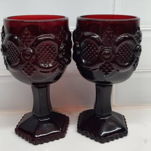 May include: Two ruby red glass goblets with a diamond pattern and a scalloped edge on the base.