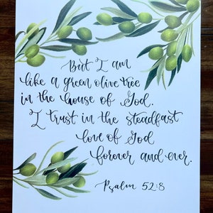 May include: A white background with a handwritten quote from Psalm 52:8. The quote reads "But I am like a green olive tree in the house of God. I trust in the steadfast love of God forever and ever." The quote is surrounded by a watercolor illustration of olive branches with green leaves and olives.