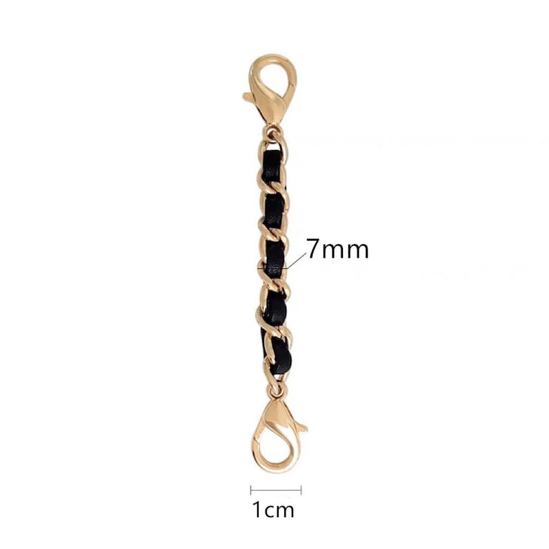 Op de afbeelding: Een gouden ketting met zwarte lederen accenten, 7 mm breed en 1 cm lang. De ketting heeft twee karabijnhaken.