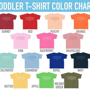 以下が含まれることがあります： 幼児用Tシャツのカラーチャート。ガーネット、レッド、ピーチ、オレンジ、ピンク、ラズベリー、モーヴ、ソルトウォーター、シャンブレー、ロイヤル、ネイビー、バター、アップル、ミリタリーグリーンなど、15色の半袖Tシャツが並び、Cousin Crewの文字がプリントされています。