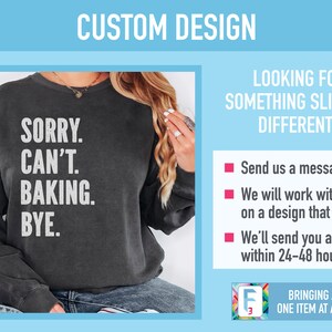May include: A black sweatshirt with the text "SORRY. CAN'T. BAKING. BYE." printed in white. The sweatshirt is being modeled by a person.