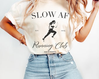 May include: A white t-shirt with the text "SLOW AF Running Club EST. 2024 JUST RUNDERFUL" and a silhouette of a runner.