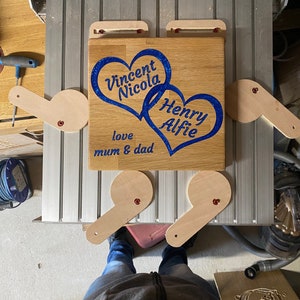 May include: A wooden plaque with two blue hearts and the names Vincent Nicola, Henry Alfie, and the text "love mum & dad".