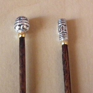 May include: Two wooden knitting needles with silver metal tips. The tips have intricate designs.