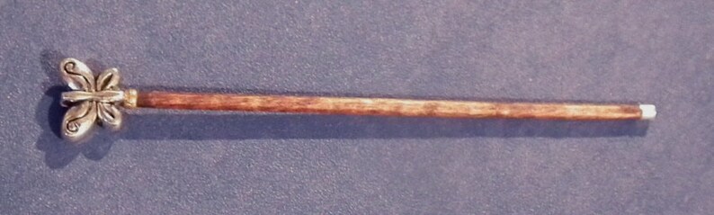 May include: A wooden walking stick with a silver butterfly design at the top.